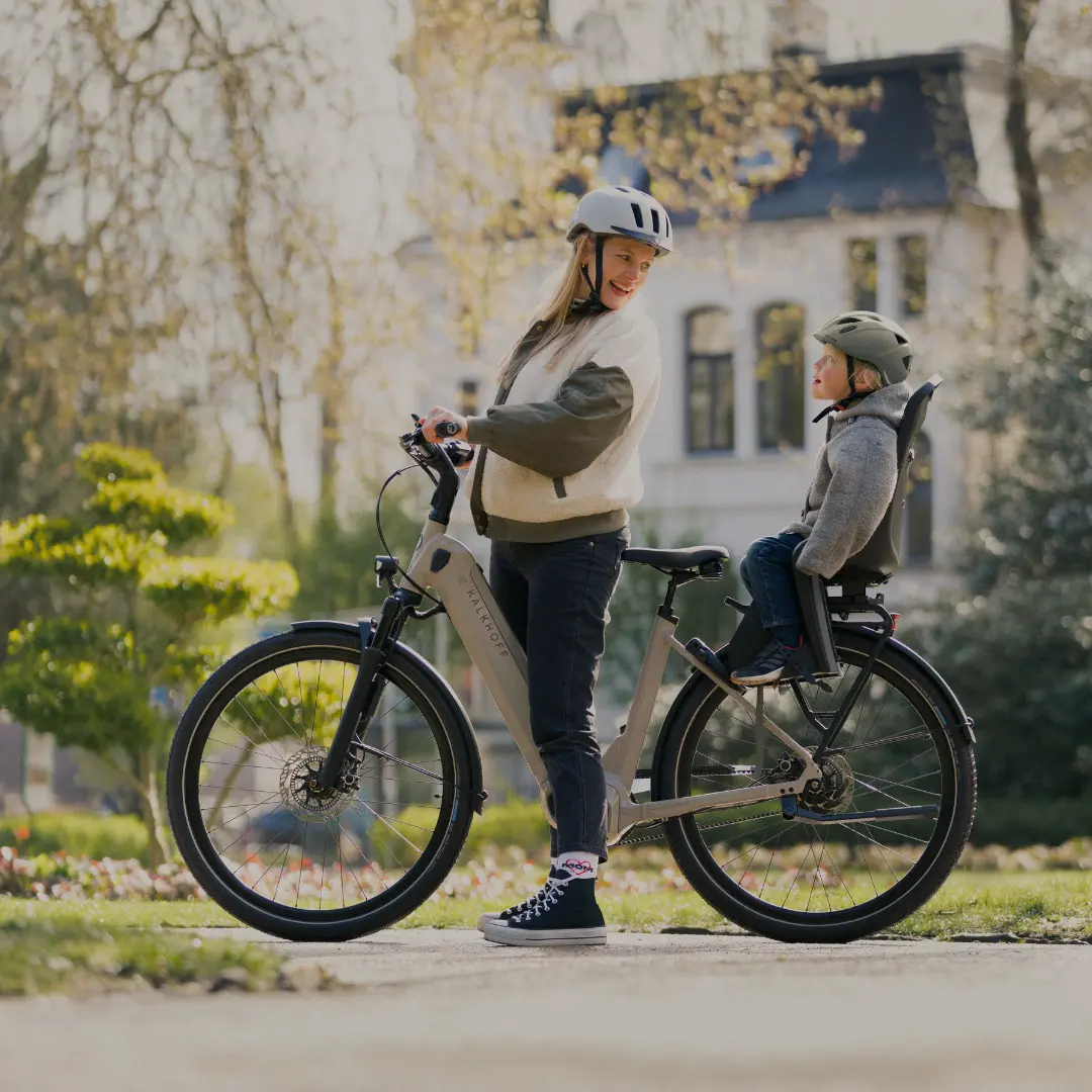 City E-Bikes Frau mit Kind im Kindersitz auf einem E-Bike im Park
