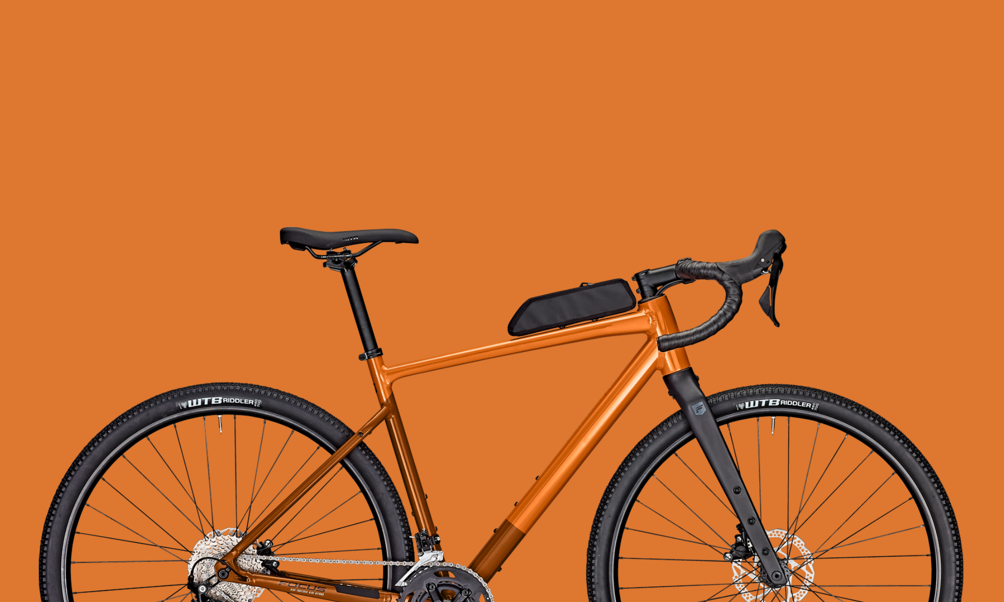 Gravelbike in Kupfer-Orange mit Oberrohrtasche vor passendem Hintergrund – breite Reifen und sportliche Geometrie für Offroad-Touren.